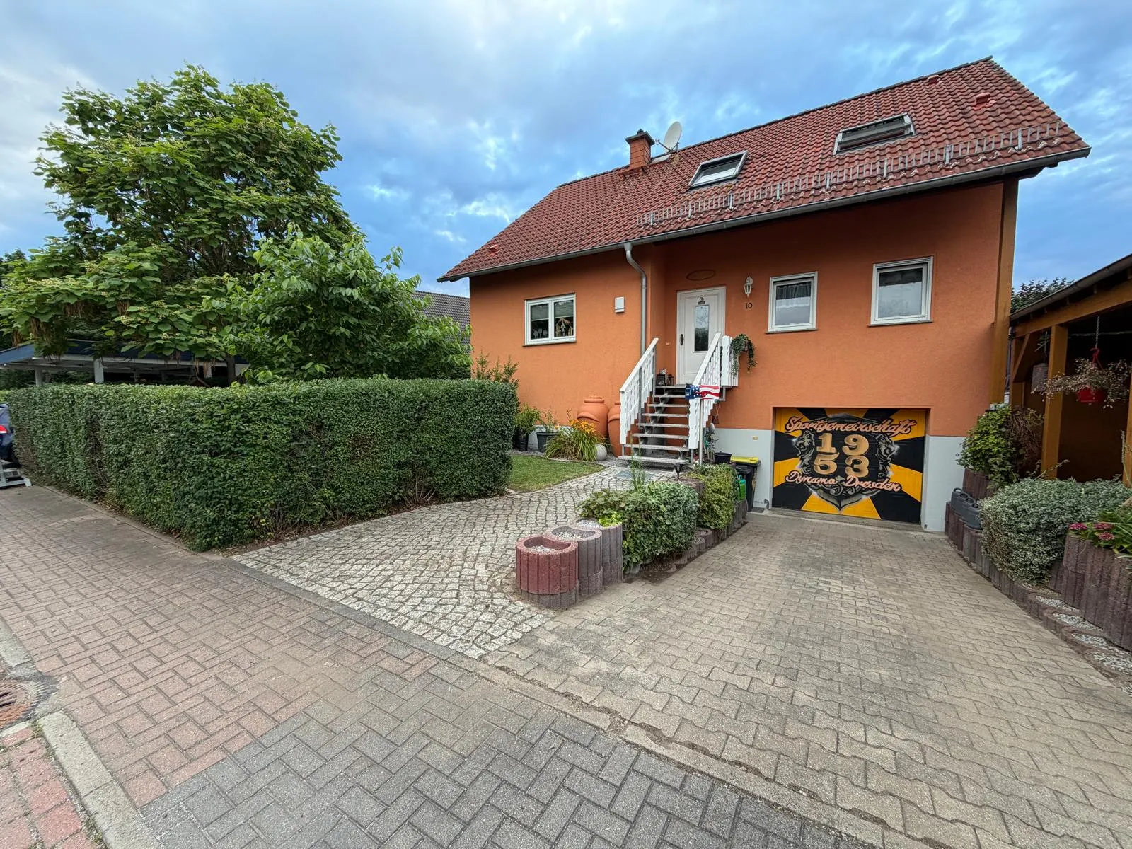 Wohnhaus mit gepflasterter Einfahrt und geschnittenen Hecken