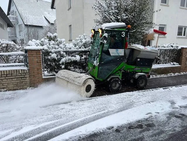 Winterdienst-Fahrzeug räumt und kehrt eine verschneite Straße frei